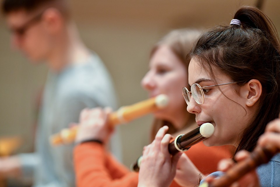 Photo of women playing a historical flute with other flautists in the background